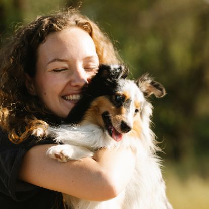 A person is hugging their dog in a field A person is hugging their dog in a field