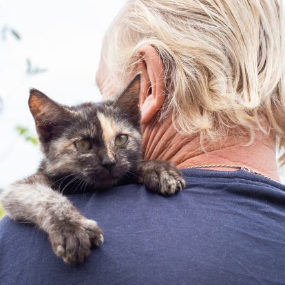 A man holding a cat on his shoulder