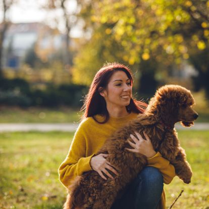 A person is sitting on the grass with their dog