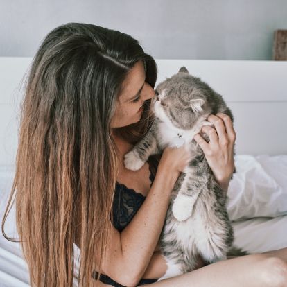 a person sitting on a bed holding a cat